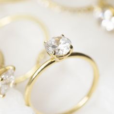 two gold wedding rings with one diamond on top and the other surrounded by white stones