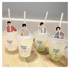 four plastic cups with stickers on the lids and straws in front of them