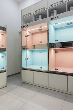 two glass display cases in a room with white walls and tile flooring, one is pink and the other is light blue