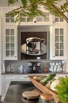 a kitchen with white cabinets and an art work on the wall above the coffee maker