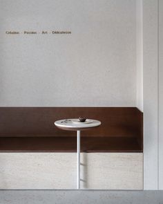 a small white table sitting on top of a wooden bench next to a wall with writing on it