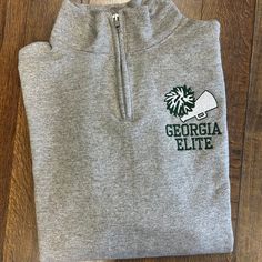 a grey sweatshirt with the words georgia little on it and a green leaf in the center