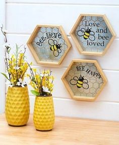 three honeycomb vases with flowers in them on a table next to a wall