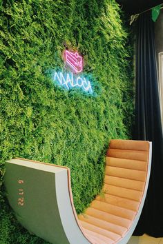 a green wall with stairs in front of it and a neon sign on the side