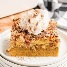 a slice of pumpkin pie on a plate with whipped cream and pecans in the background