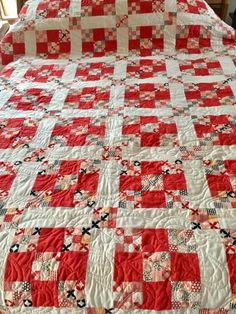 a large red and white quilt on top of a bed