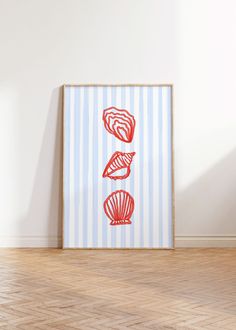 three seashells on blue and white striped wall in an empty room with wood flooring