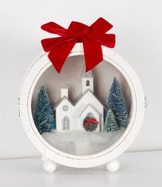 a christmas ornament with a red bow on it's head and a church in the background