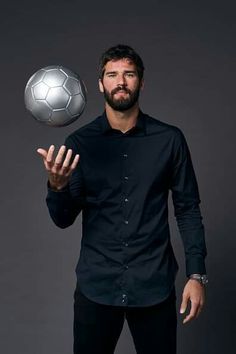 a man is holding a soccer ball in his right hand and posing for the camera