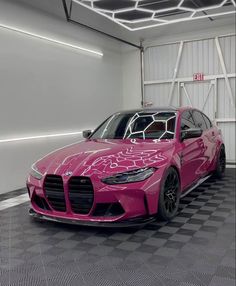 a pink sports car parked in a garage with checkered flooring and white walls