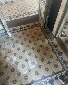 an old tile floor with black and white designs on it, in front of a door