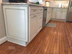 a kitchen with wood floors and white cabinets