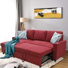 a living room scene with focus on the red couch and pillows in the foreground