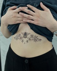 a woman with a bee tattoo on her stomach is holding her hands to her chest