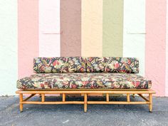 a couch sitting on top of a wooden frame in front of a wall with multicolored stripes