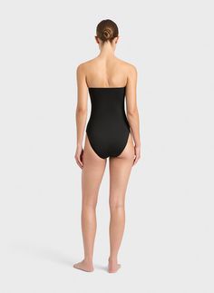 The Dahlia bandeau one piece in black features a deep V wire that offers a sensual plunge front. With feature ruching over the bust panels, Dahlia is designed to be worn either as a strapless swimsuit or as a halterneck. This elegant swimsuit features a removable rouleau halterneck strap, gripper tape along the top edge and boning at the sides to maintains shape and support and you can feel comfortable and confident when wearing it strapless. Self-lined in our luxuriously soft, yet supportive, I Chic Strapless Seamless Swimwear, Strapless Swimwear With Built-in Bra, Black Strapless Swimwear, Black Bandeau Swimwear With Lined Body, Black Ruched Bandeau Swimwear, Strapless Nylon Swimwear, Strapless Seamless Swimwear For Party, Black Strapless Seamless Swimwear, Strapless Seamless Party Swimwear