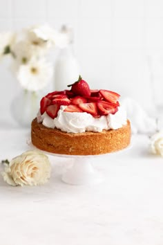 a cake with whipped cream and strawberries on top is sitting on a white table