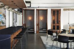 an empty restaurant with tables and chairs in front of the bar, along with several stools