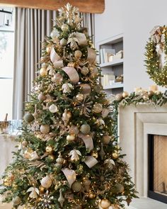 a christmas tree decorated with gold and silver ornaments in a living room next to a fireplace