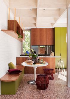 a kitchen with green walls and white ceilinging next to a dining table in the center