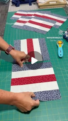 someone is cutting fabric with scissors on top of the quilting board and another person is using a pair of scissors to cut it