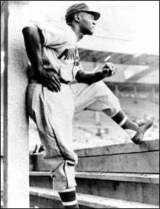 an old black and white photo of a baseball player leaning on the bleachers