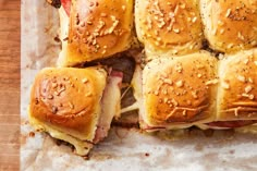 several sliders with meat and cheese on them sitting on a piece of parchment paper