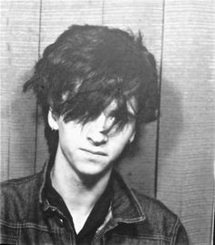 black and white photograph of young man with messy hair in jail cell, looking at camera