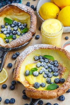 blueberries and lemon custard tarts with powdered sugar on the rim