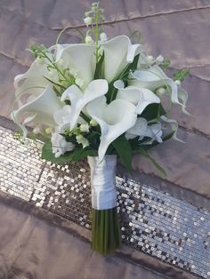 a bouquet of white flowers sitting on top of a silver sequin tablecloth covered floor