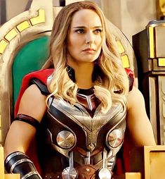 a woman dressed as the avengers stands in front of an iron man suit and armor