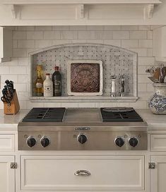 a stove top oven sitting inside of a kitchen next to white cabinets and counter tops