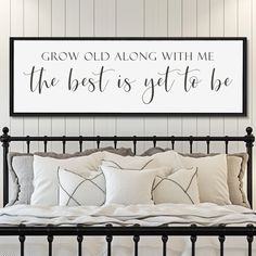 a bedroom with a bed, pillows and a framed sign above it that says grow old along with me the best is get to be