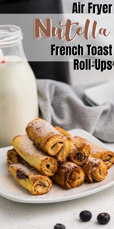 an air fryer filled with french toast rolls on top of a white plate next to a glass of milk