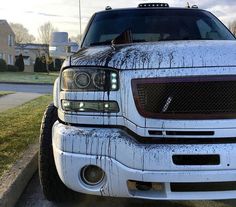 the front end of a white truck with snow on it's hood and headlights