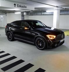 a black car parked in an underground parking garage with no one around it or on the ground