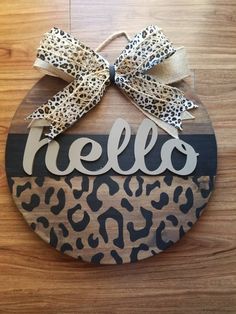 a wooden sign that says hello with a leopard print bow on the front and word hello