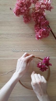 someone is working with some flowers on a wooden table and the words make a wreath with me