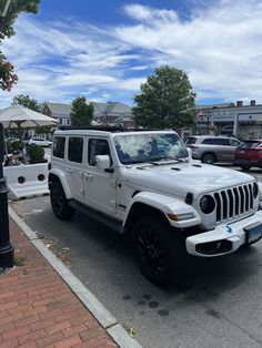 a white jeep parked on the side of a road next to a parking meter and umbrella