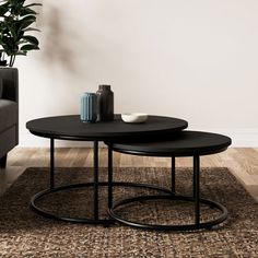 two black tables sitting on top of a rug in front of a gray couch and chair