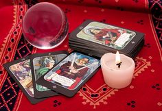 some cards and a candle on a red table cloth with a glass ball in the middle