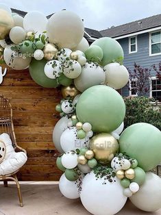 a bunch of balloons that are in the shape of an arch with green, white and gold decorations