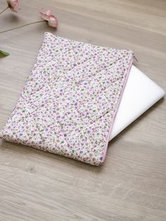 a laptop computer sitting on top of a wooden table next to flowers and a vase