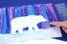 someone holding up a polar bear cut out of paper with stars in the sky behind it