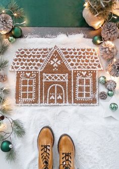 a pair of brown shoes sitting on top of a snow covered floor next to a gingerbread house