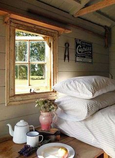 a bed with two pillows on top of it next to a window and tea pot