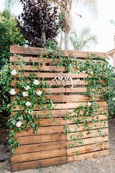 a wooden fence with flowers and greenery on the top that says welcome to you