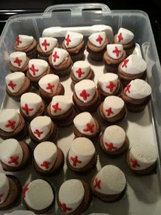 cupcakes with white frosting and red crosses are arranged in a plastic container