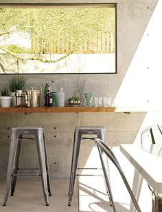 two metal stools sitting in front of a counter