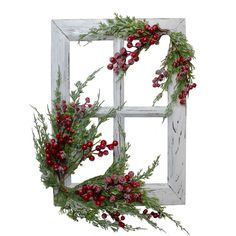 an old window frame decorated with red berries and greenery is hanging on the wall